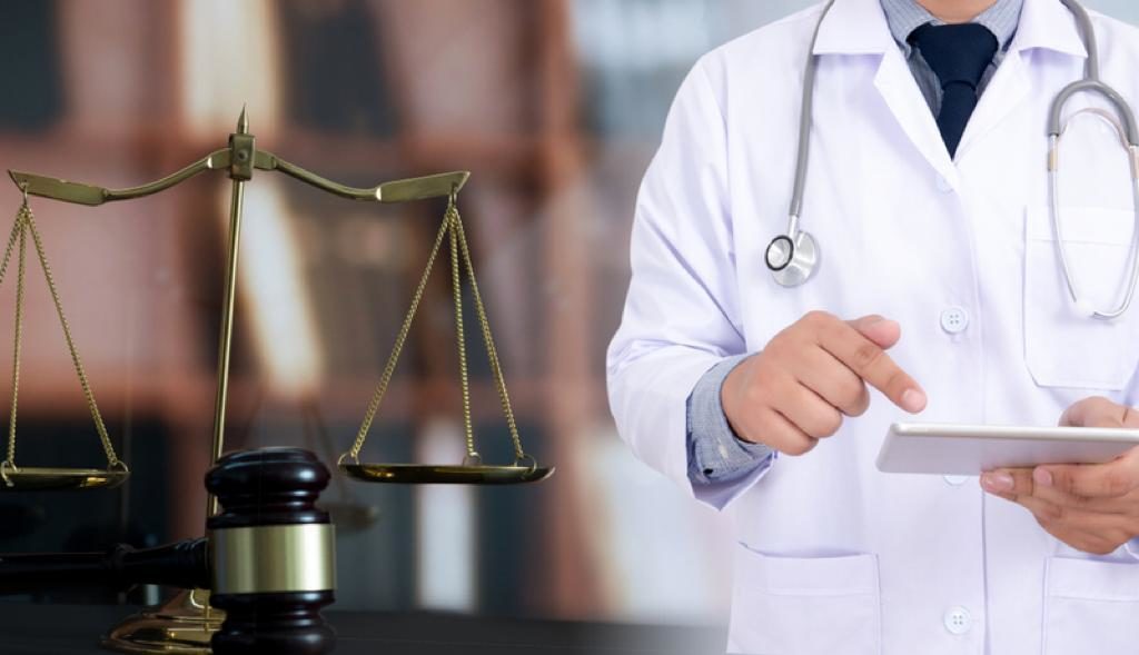 A doctor reviewing records beside the scales of justice
